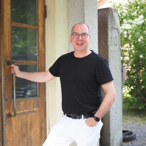 Vakka-Suomen musiikkiopiston rehtori Jussi Kauranen katsoo hymyillen kameraan ja pitää vanhanaikaisesta ulko-ovesta kiinni.